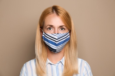 Photo of Woman wearing handmade cloth mask on beige background. Personal protective equipment during COVID-19 pandemic
