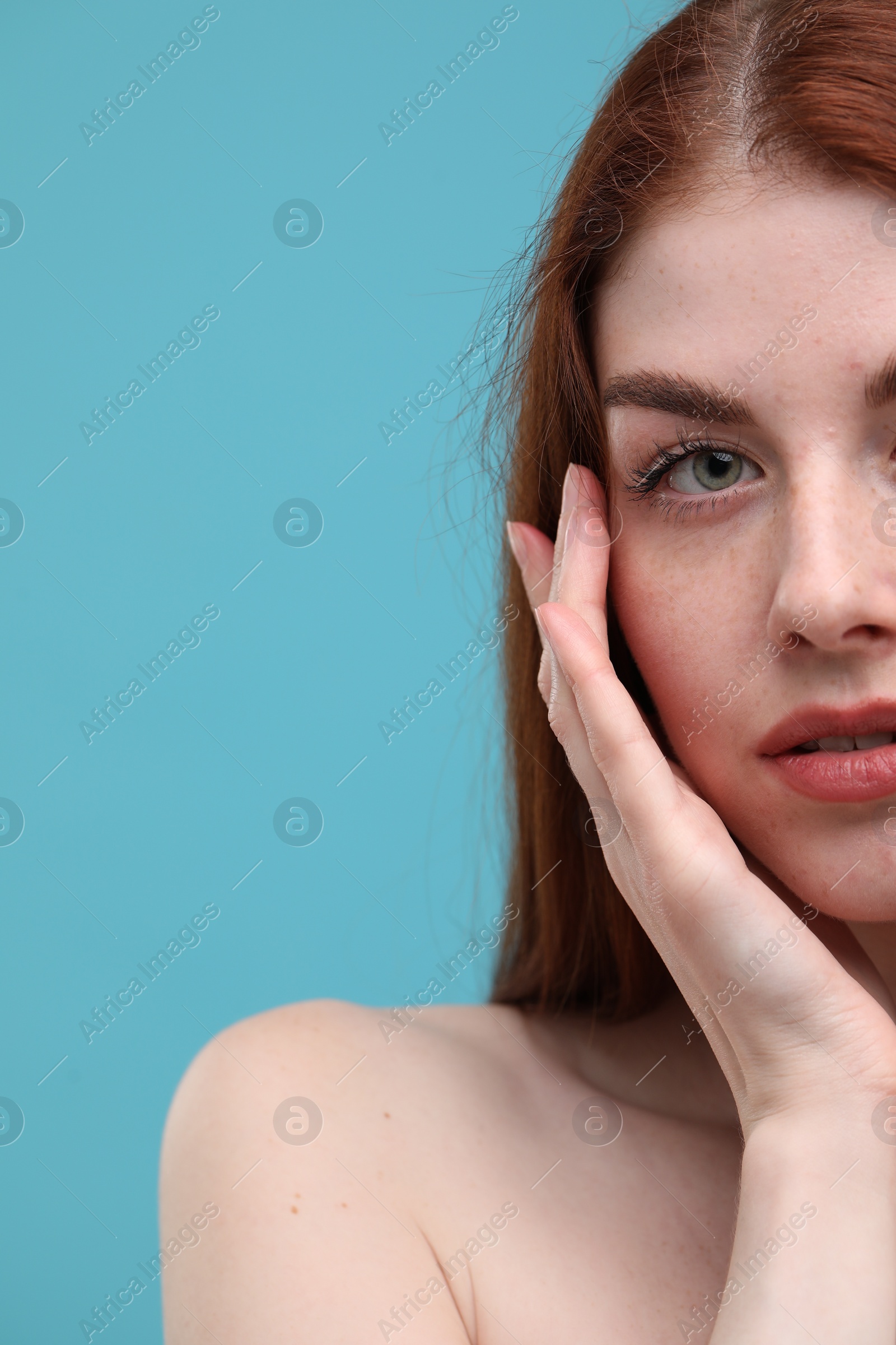 Photo of Beautiful woman with freckles on light blue background, closeup