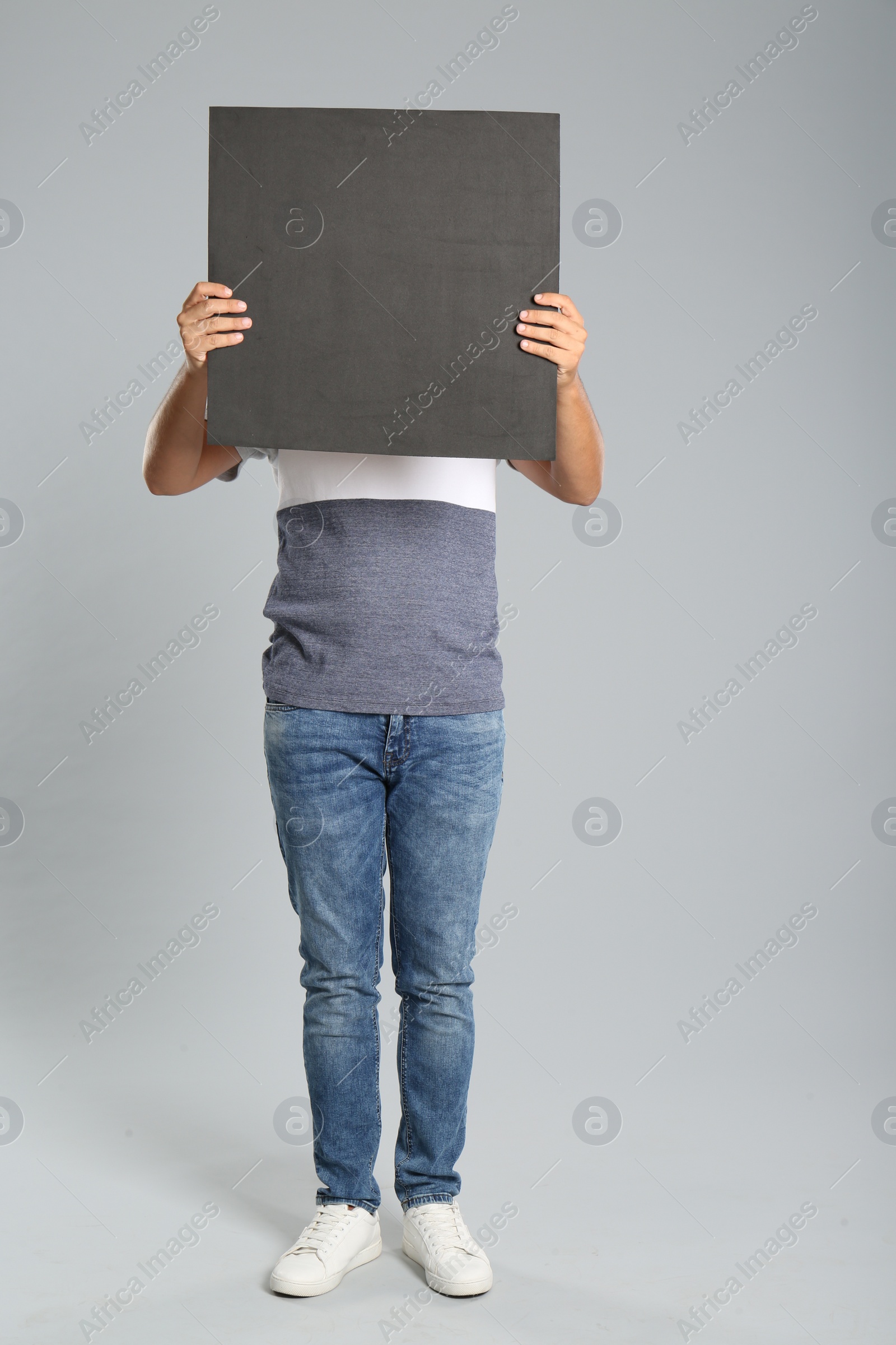 Photo of Man holding black blank poster on grey background. Mockup for design