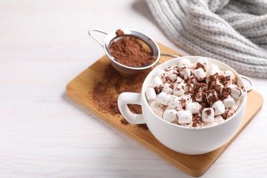 Photo of Cup of aromatic hot chocolate with marshmallows and cocoa powder on light wooden table, closeup. Space for text