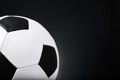Photo of Football ball on black background, closeup. Space for text