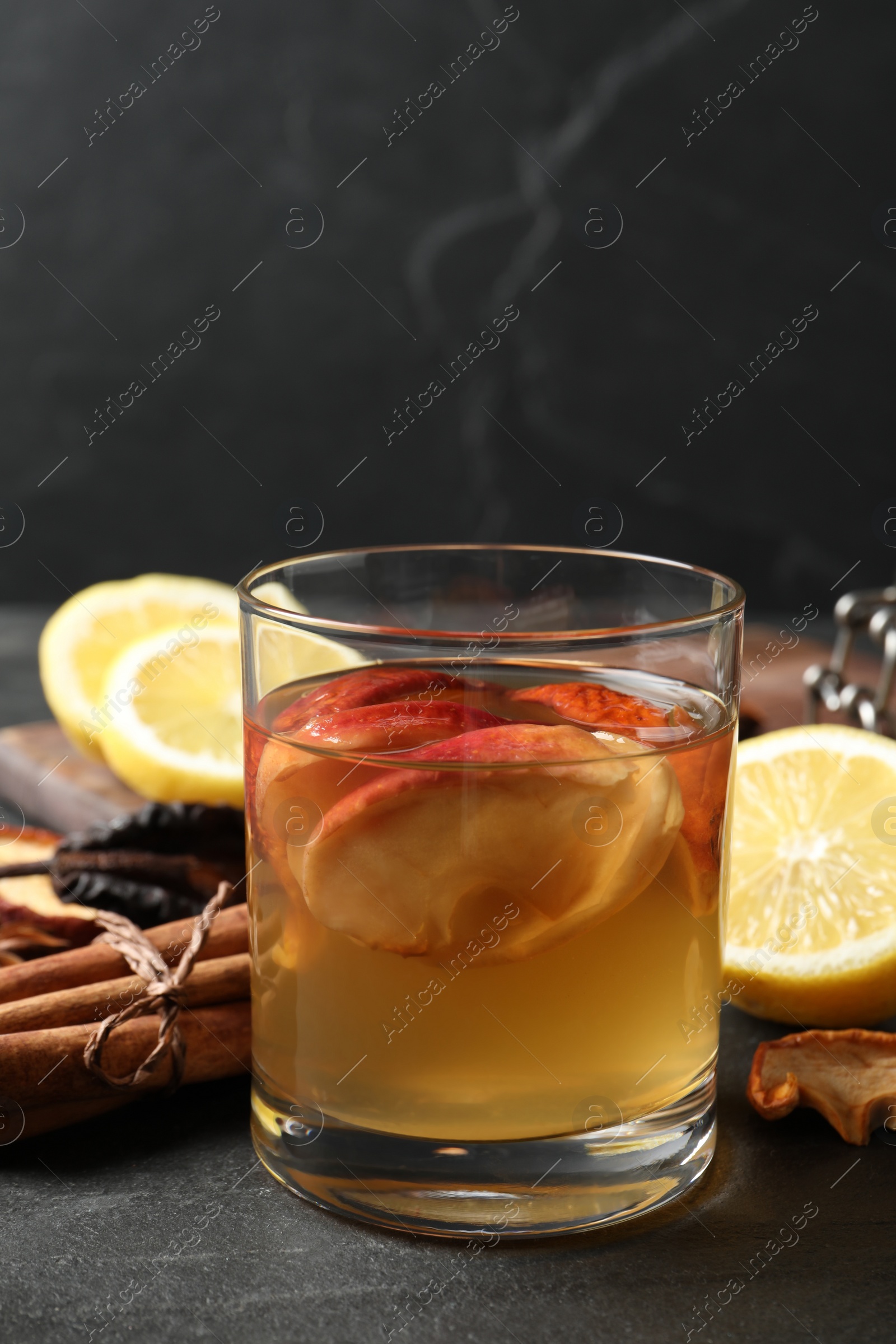 Photo of Delicious compote with dried apple slices in glass on black table