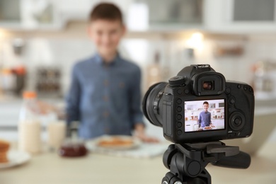 Photo of Cute little blogger with food on camera screen, closeup