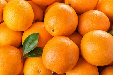 Photo of Pile of fresh ripe oranges with leaves as background, top view