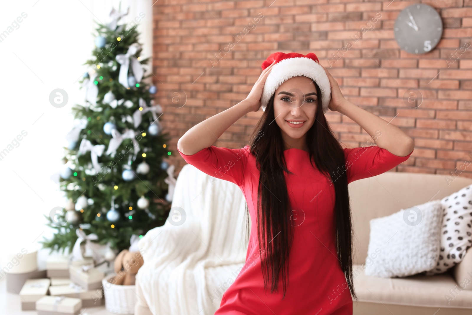 Photo of Beautiful young woman in Santa hat at home. Celebrating Christmas