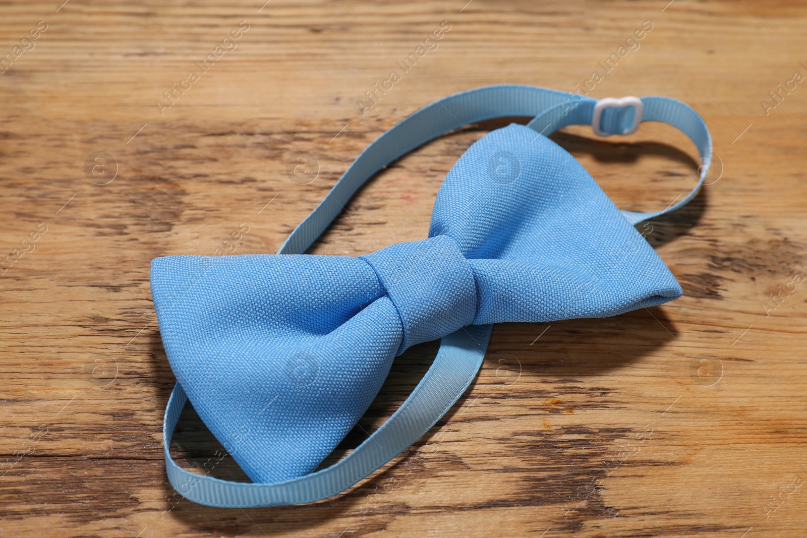 Photo of Stylish light blue bow tie on wooden table, closeup