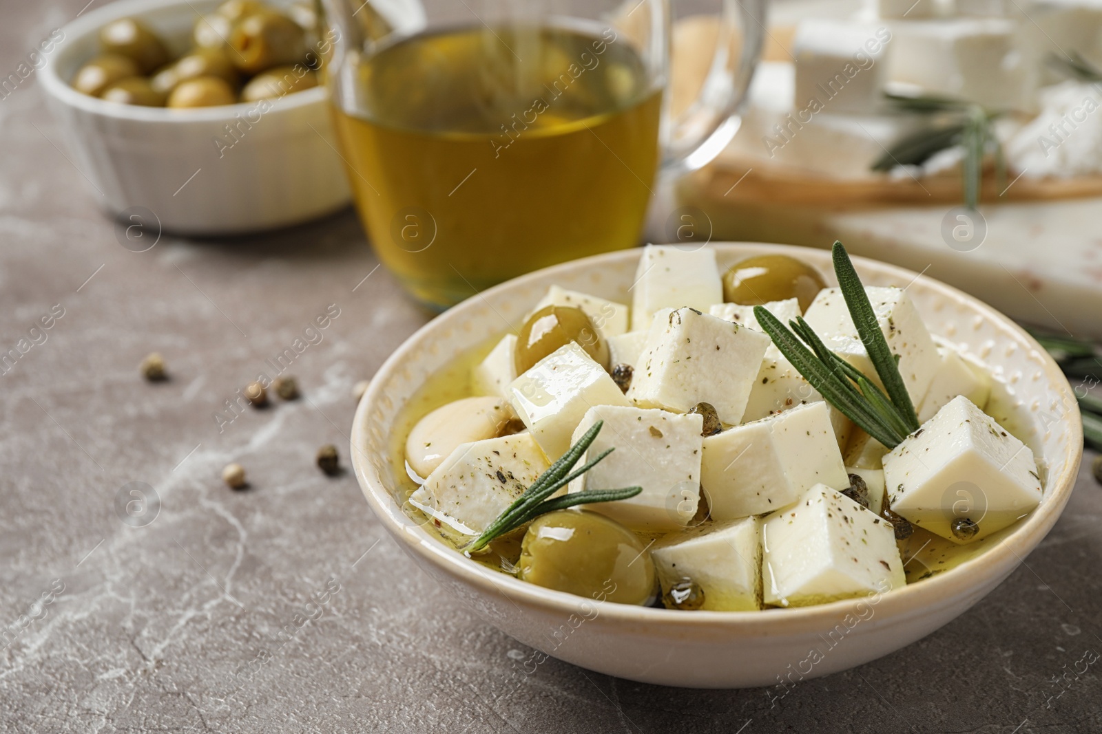 Photo of Composition with pickled feta cheese in bowl on light brown table