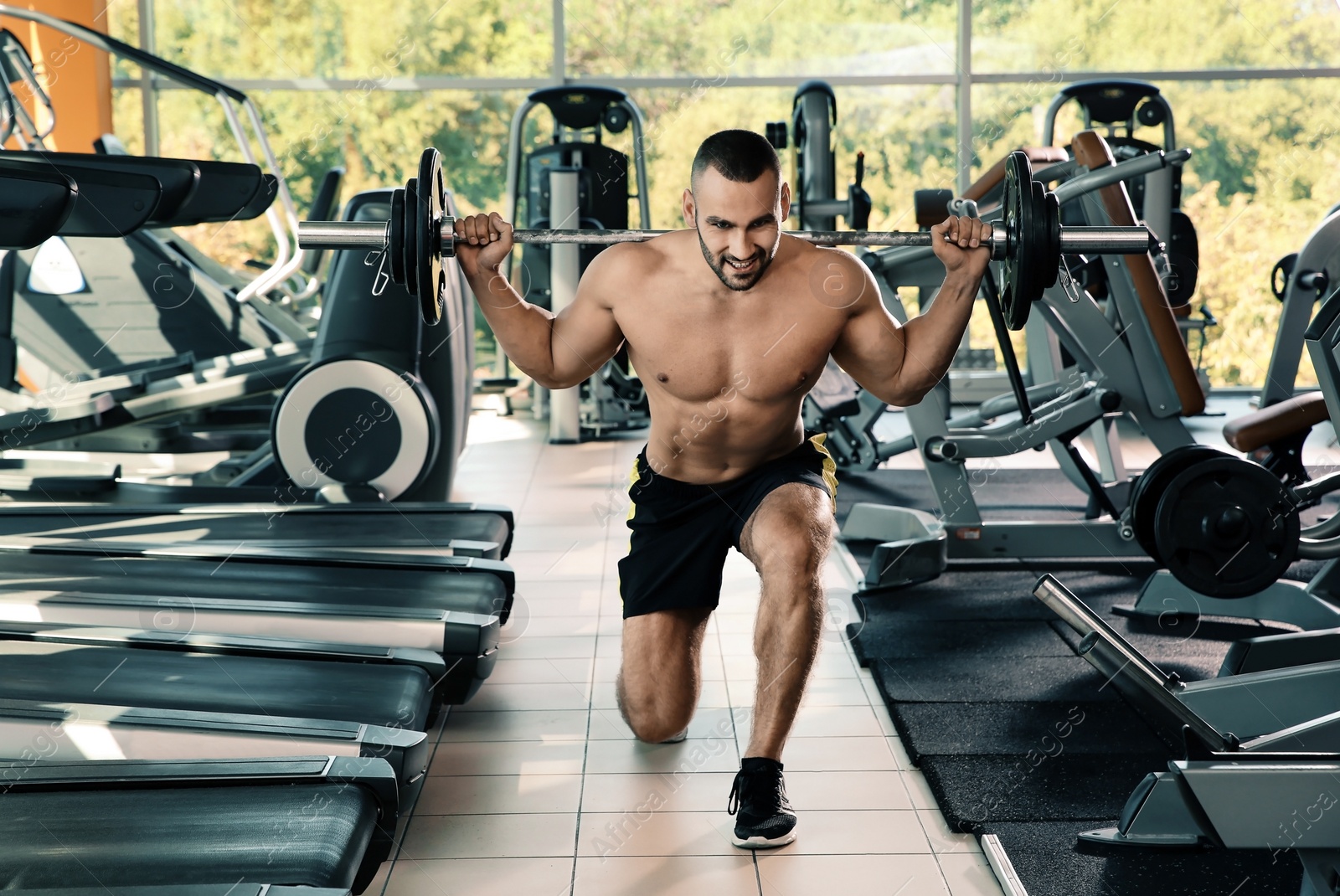 Photo of Strong young man lifting barbell in gym