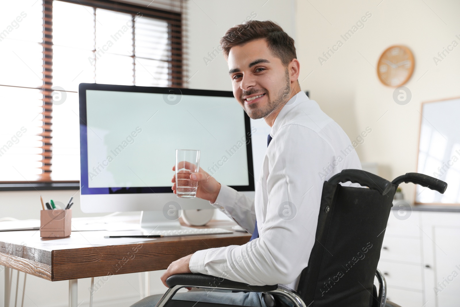 Photo of Portrait of man in wheelchair and computer on table indoors. Space for text