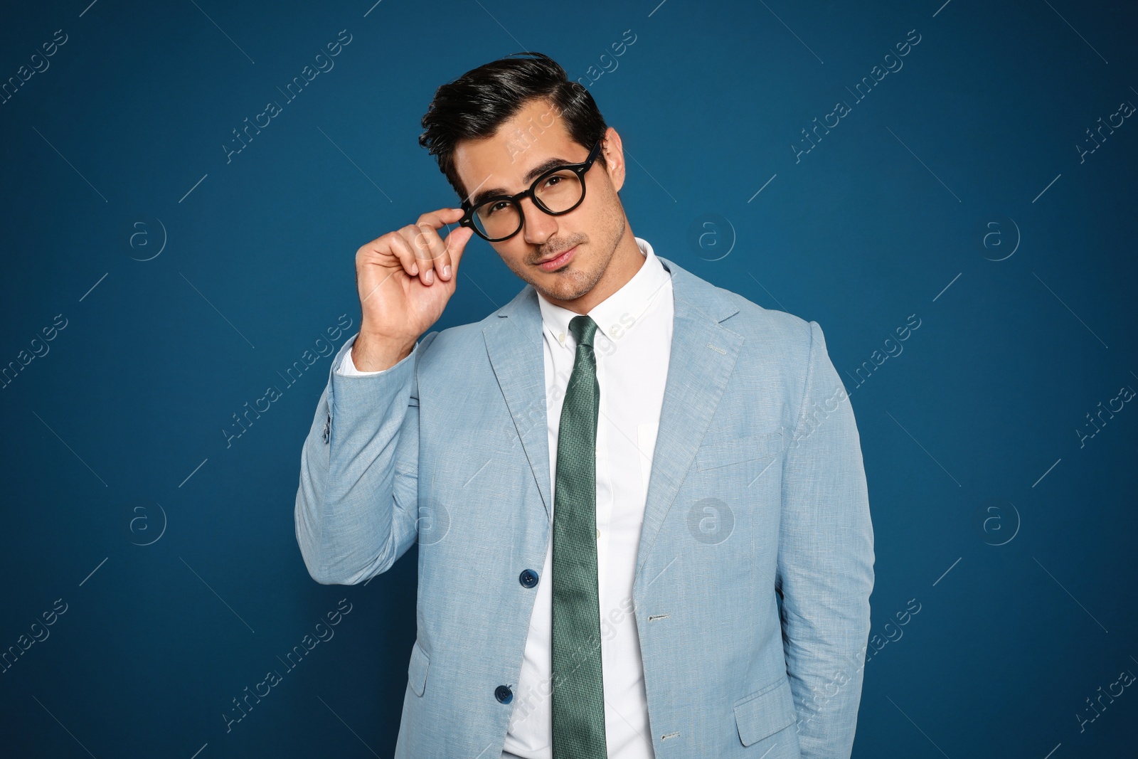 Photo of Portrait of handsome young businessman wearing glasses on blue background