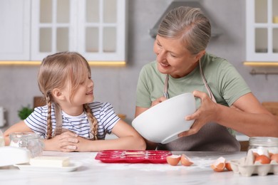 Happy grandmother with her granddaughter cooking together in kitchen