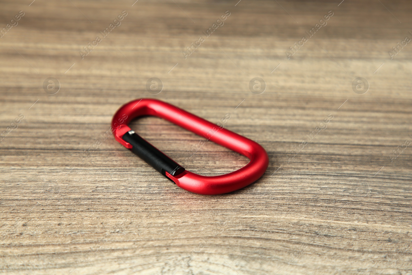 Photo of One red metal carabiner on wooden table