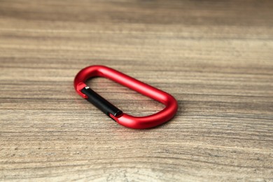 One red metal carabiner on wooden table