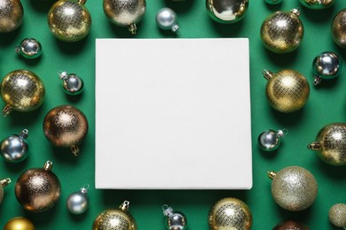 Photo of Blank canvas and Christmas baubles on green background, flat lay. Space for design