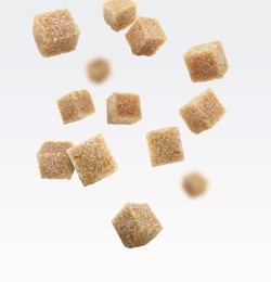 Image of Brown cane sugar cubes falling on white background