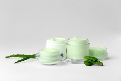 Photo of Jars of body cream with aloe extract on white background