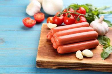 Photo of Fresh raw vegetarian sausages and vegetables on light blue wooden table, closeup
