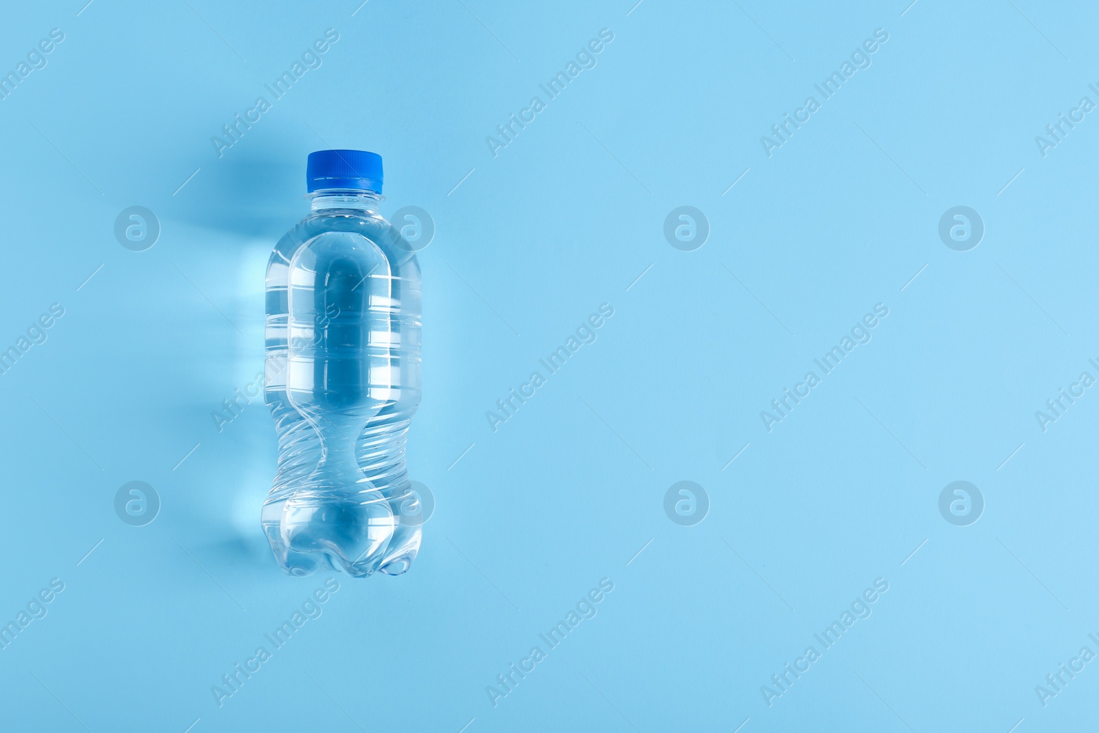 Photo of Bottle of water on color background, top view. Space for text