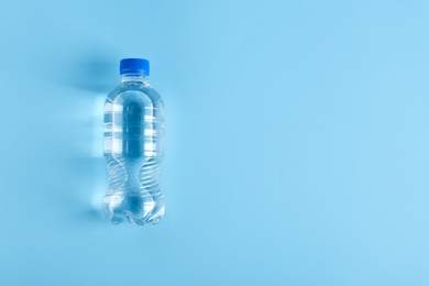 Bottle of water on color background, top view. Space for text