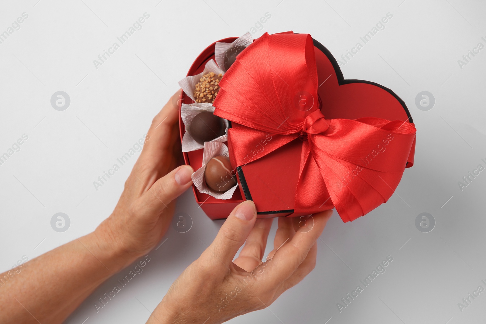 Photo of Woman with box of delicious chocolate candies on white background, above view