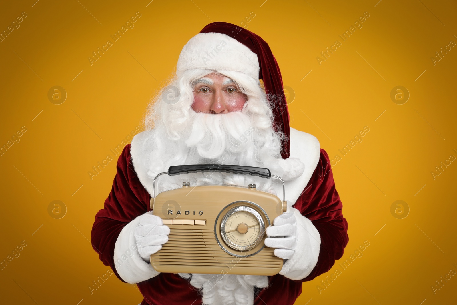 Photo of Santa Claus with vintage radio on yellow background. Christmas music