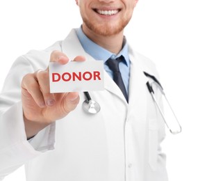 Doctor holding card with word DONOR on white background, closeup