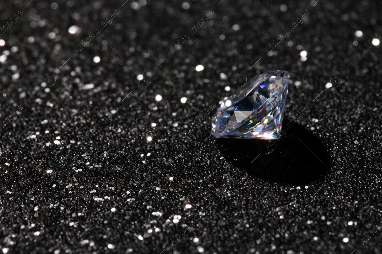 Photo of Beautiful dazzling diamond on dark shiny background. Space for text
