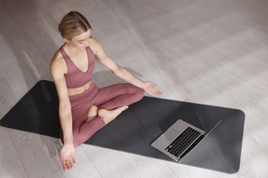 Photo of Beautiful woman watching online yoga class at home