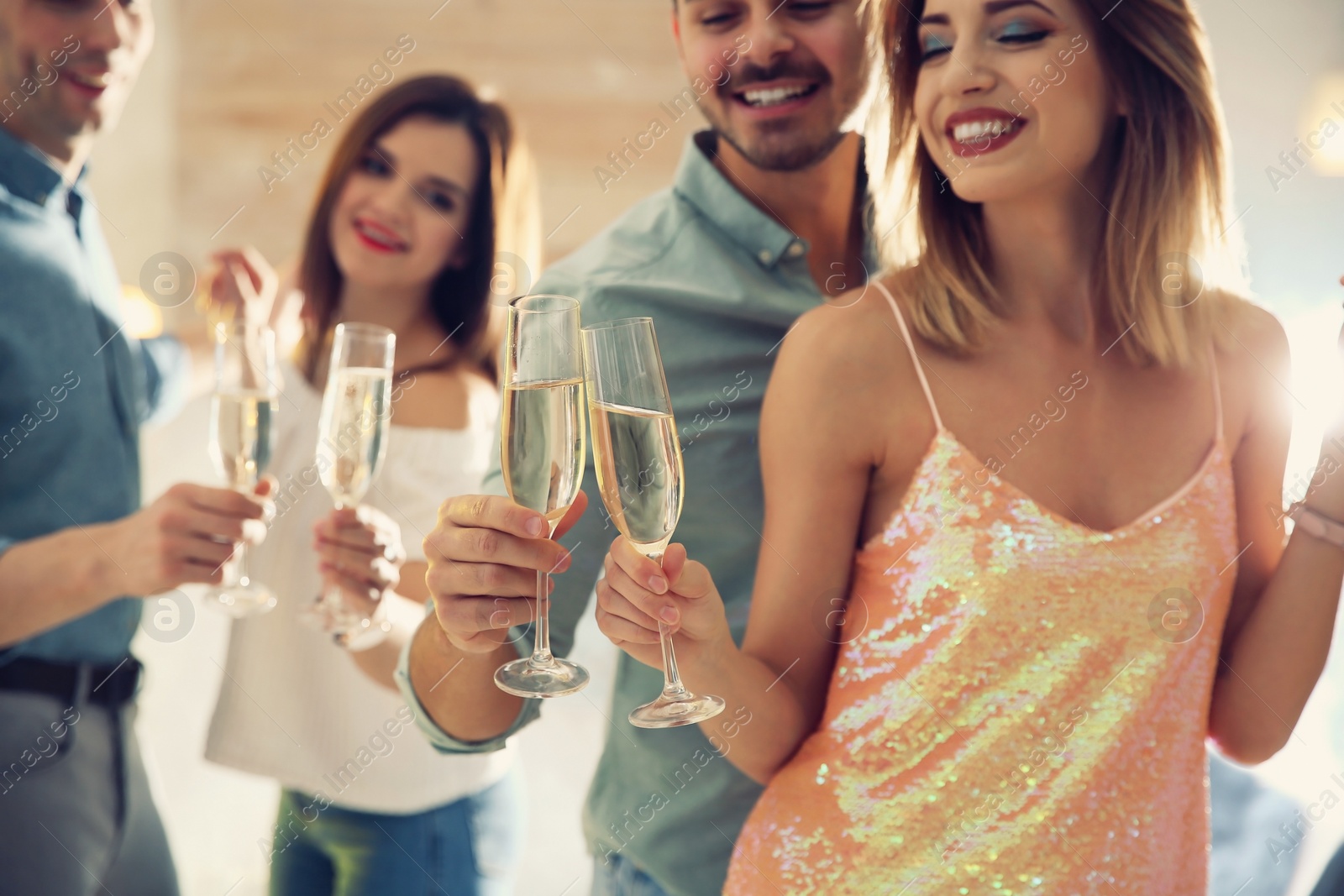 Photo of Friends clinking glasses with champagne at party indoors