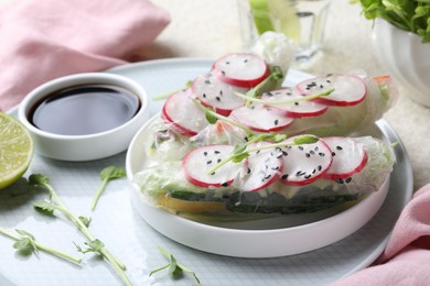 Photo of Delicious spring rolls, microgreens and soy sauce on table, closeup