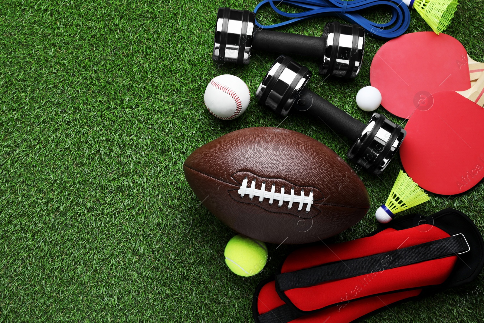 Photo of Set of different colorful sports equipment on green grass, flat lay. Space for text