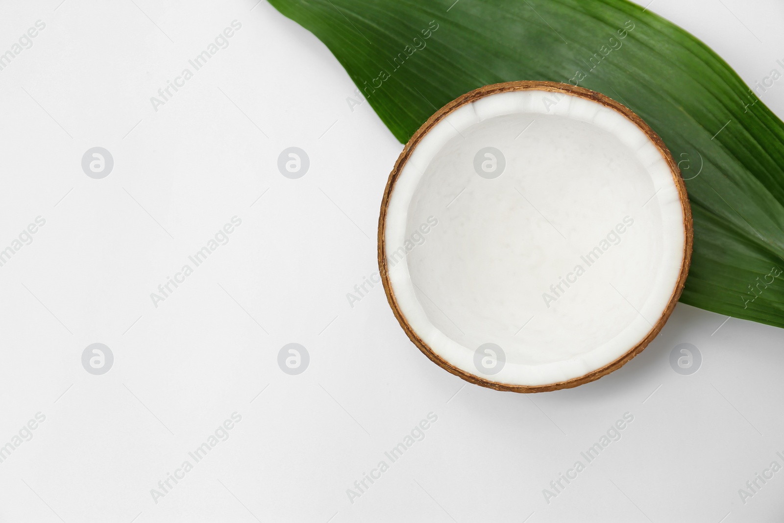 Photo of Half of fresh coconut and palm leaf on white background, top view