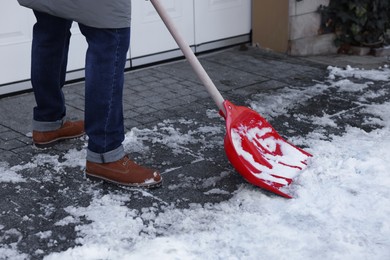 Photo of Man removing snow with shovel near building outdoors, closeup