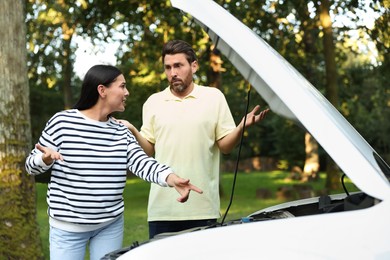 Stressed couple near broken car outdoors on summer day