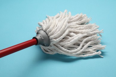 Mop with plastic handle on light blue background, closeup