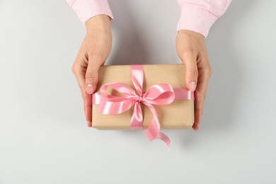 Photo of Woman holding gift box on light background, top view