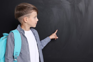 Cute schoolboy near chalkboard, space for text