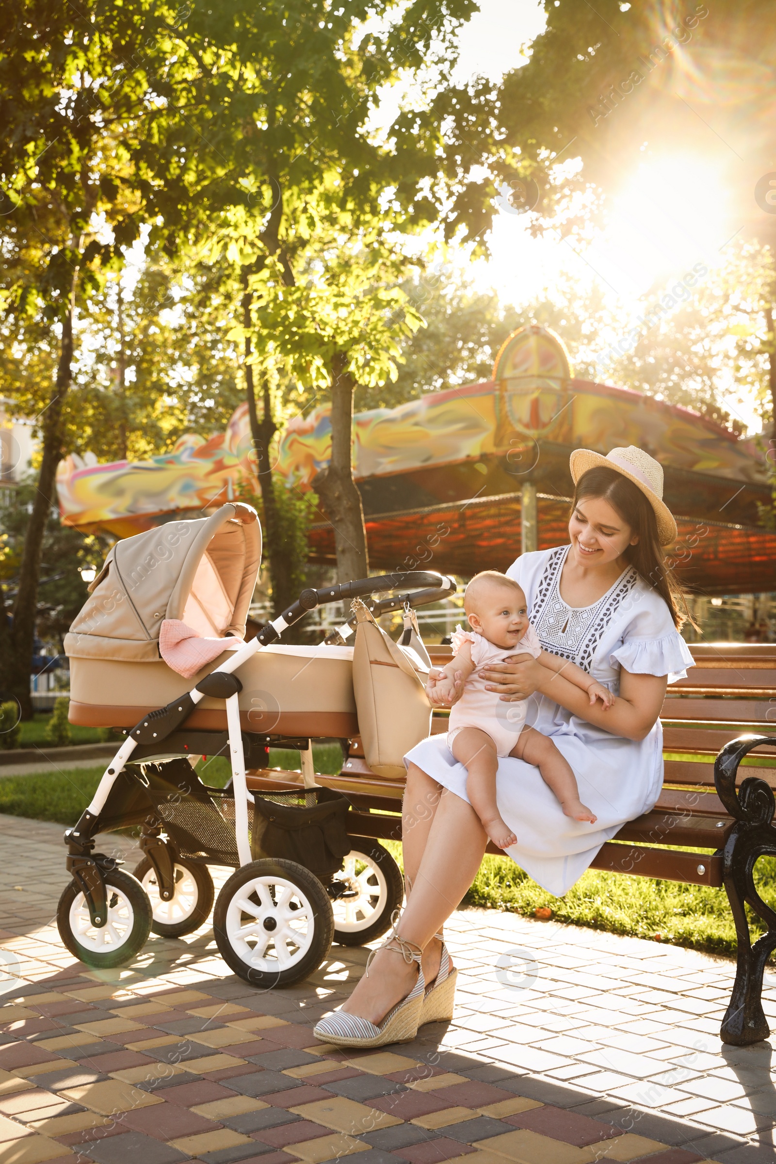 Photo of Happy mother with baby sitting on bench in park