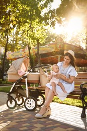 Happy mother with baby sitting on bench in park