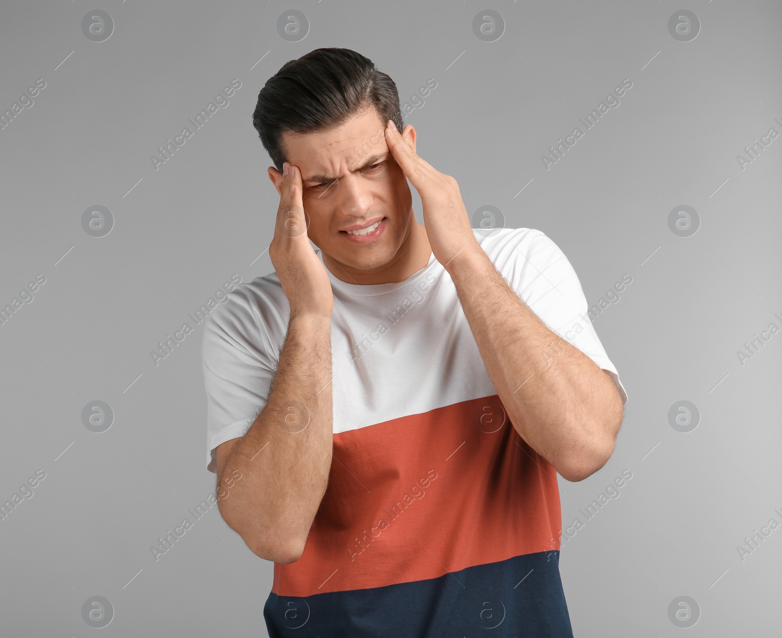 Photo of Young man suffering from headache on grey background