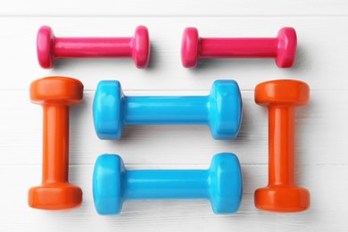 Photo of Different dumbbells on white wooden table, flat lay