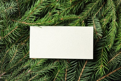 Photo of Blank card on fir tree branches, top view. Space for text