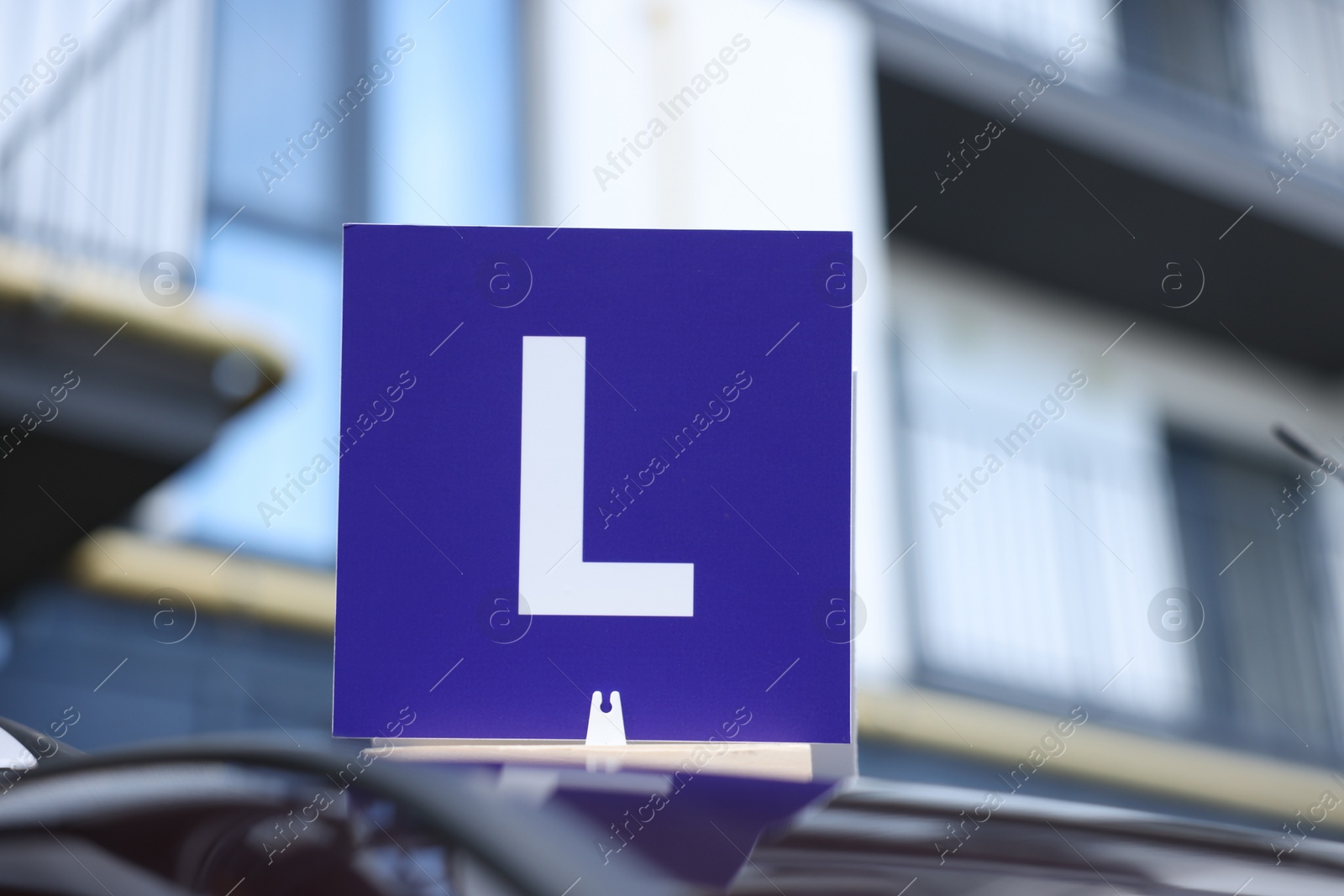 Photo of L-plate on car roof outdoors. Driving school