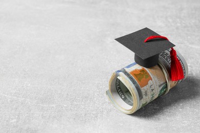 Photo of Scholarship concept. Graduation cap and banknotes on light grey table, space for text