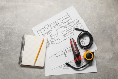 Wiring diagrams, wires and tools on grey table, flat lay