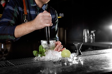 Barman making Mojito cocktail at counter in pub, closeup. Space for text