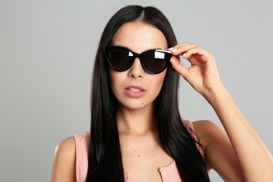 Photo of Beautiful woman wearing sunglasses on grey background