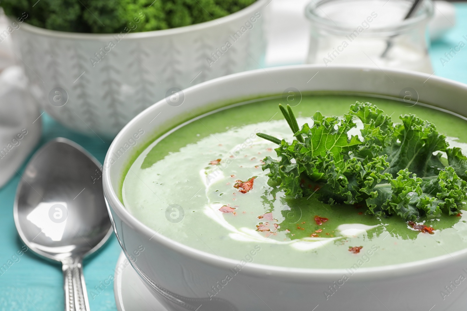Photo of Tasty kale soup on light blue wooden table, closeup