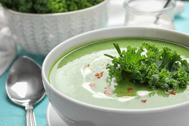 Photo of Tasty kale soup on light blue wooden table, closeup