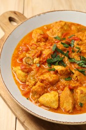Photo of Delicious chicken curry with parsley on wooden table